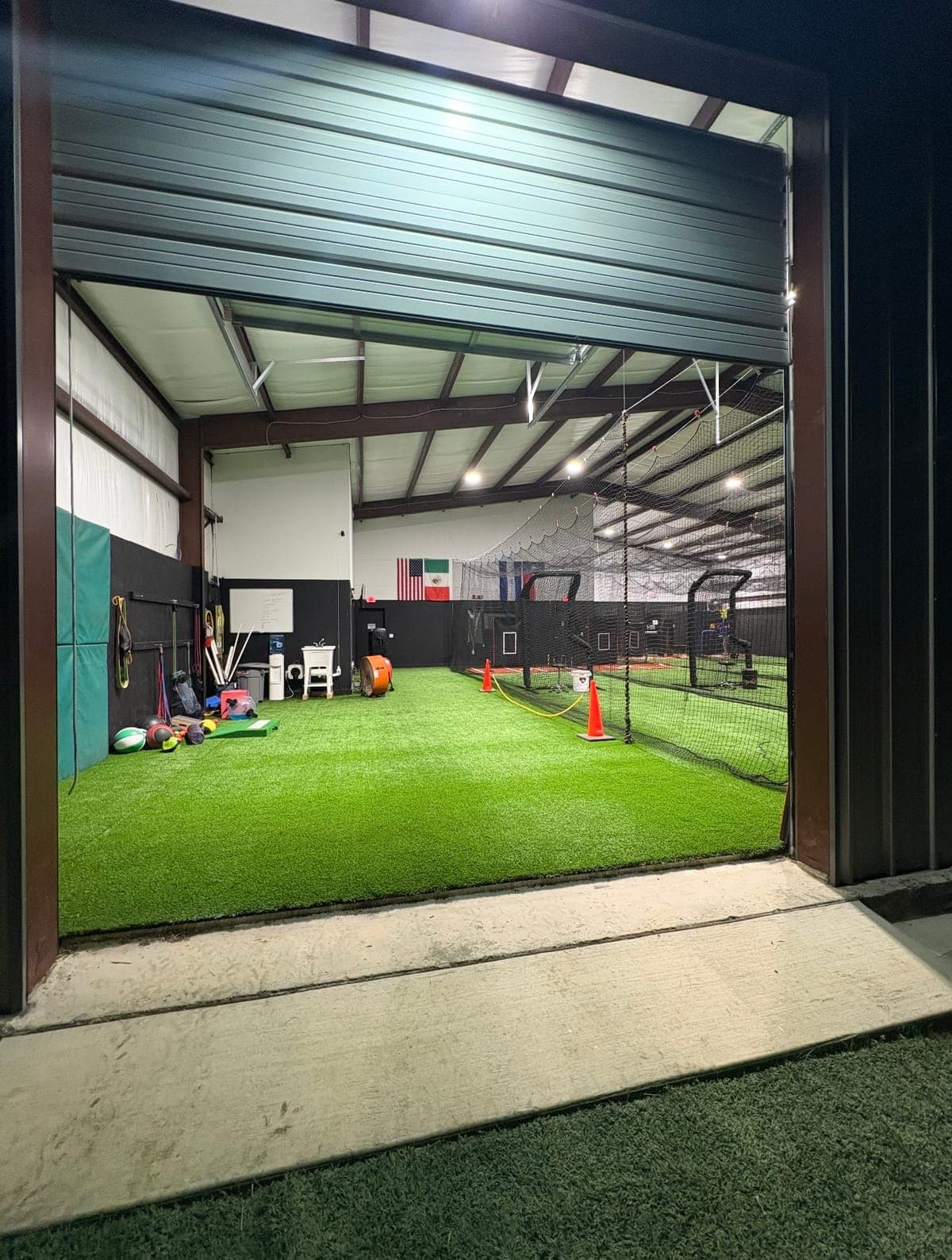 Entrance to an indoor training floor with cages, equipment, and open turf